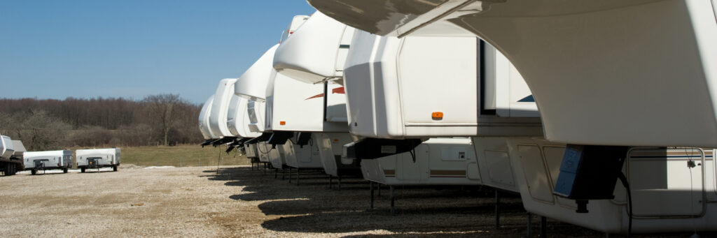 RVs and trailers parked in a gravel lot