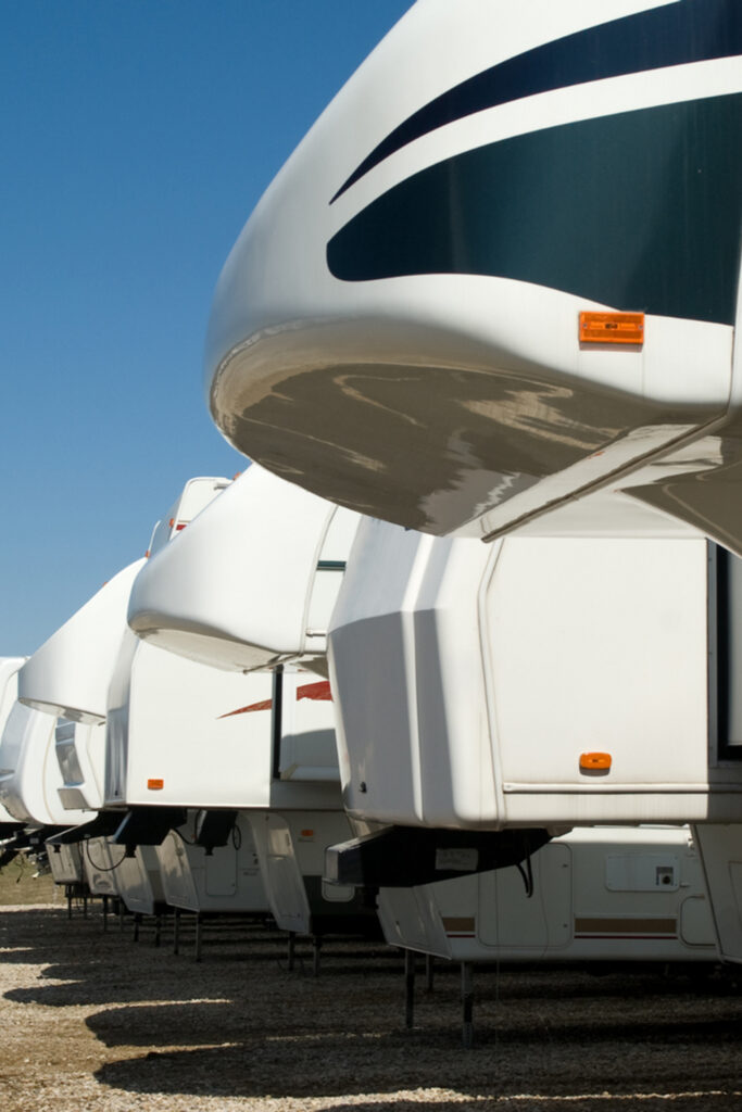 RVs and trailers parked in a gravel lot