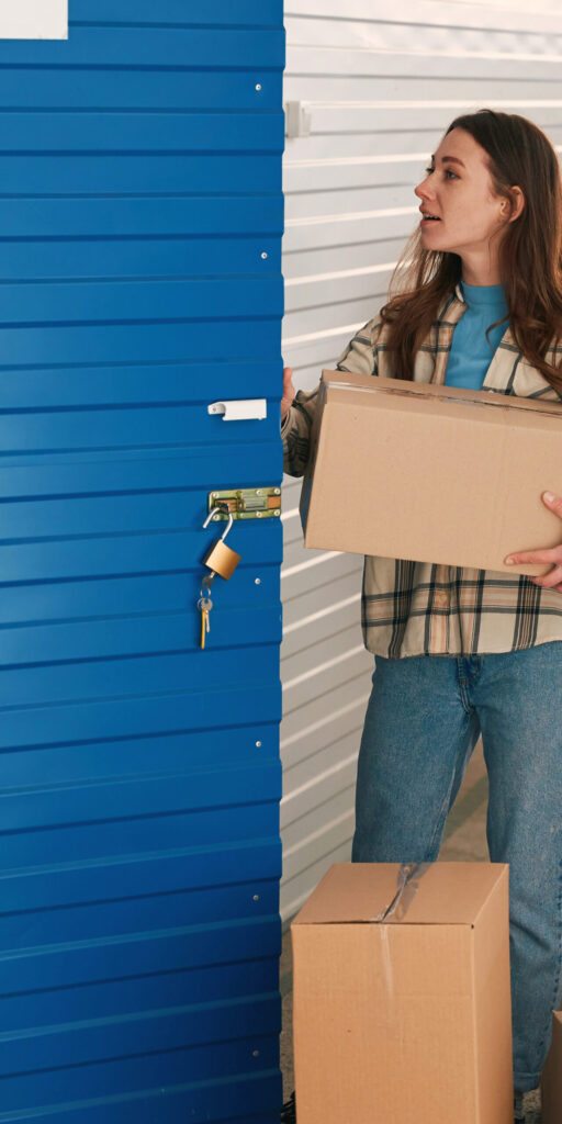 Young woman and man with big cardboard boxes into warehouse