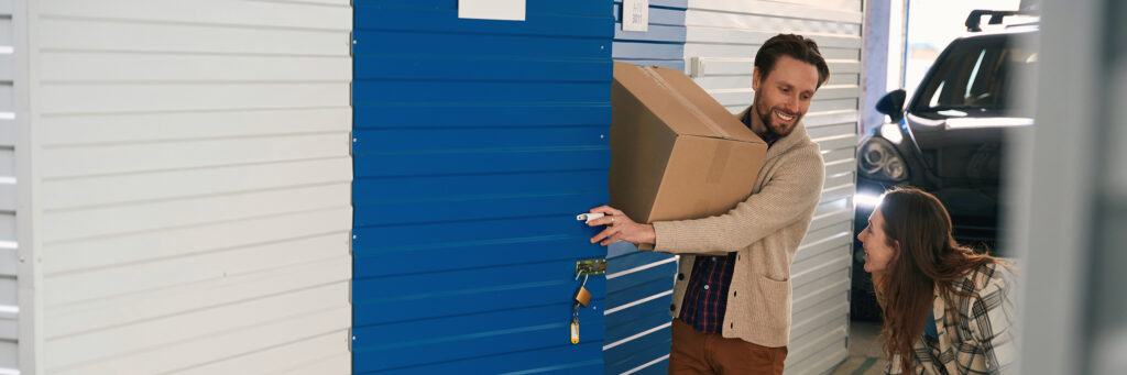 Young woman and man with big cardboard boxes into warehouse