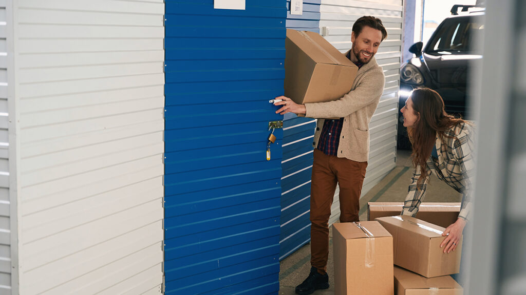 Young woman and man with big cardboard boxes into warehouse