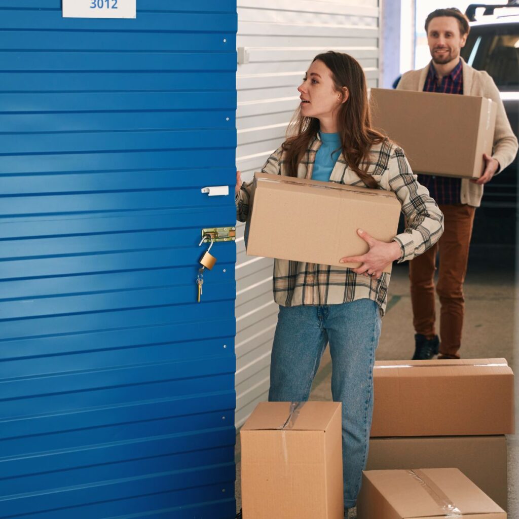 Young woman and man with big cardboard boxes into warehouse