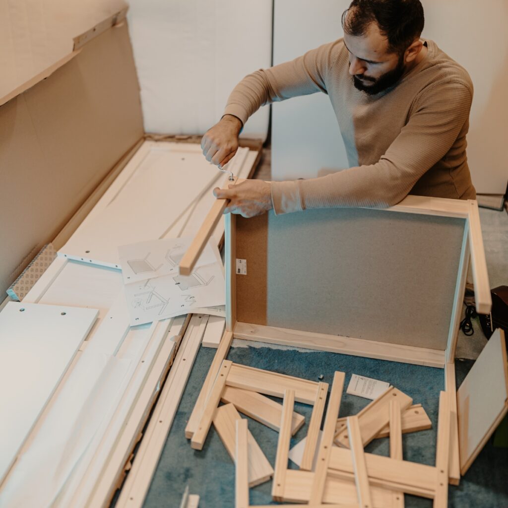 Skilled man disassembles wooden furniture with a hex key