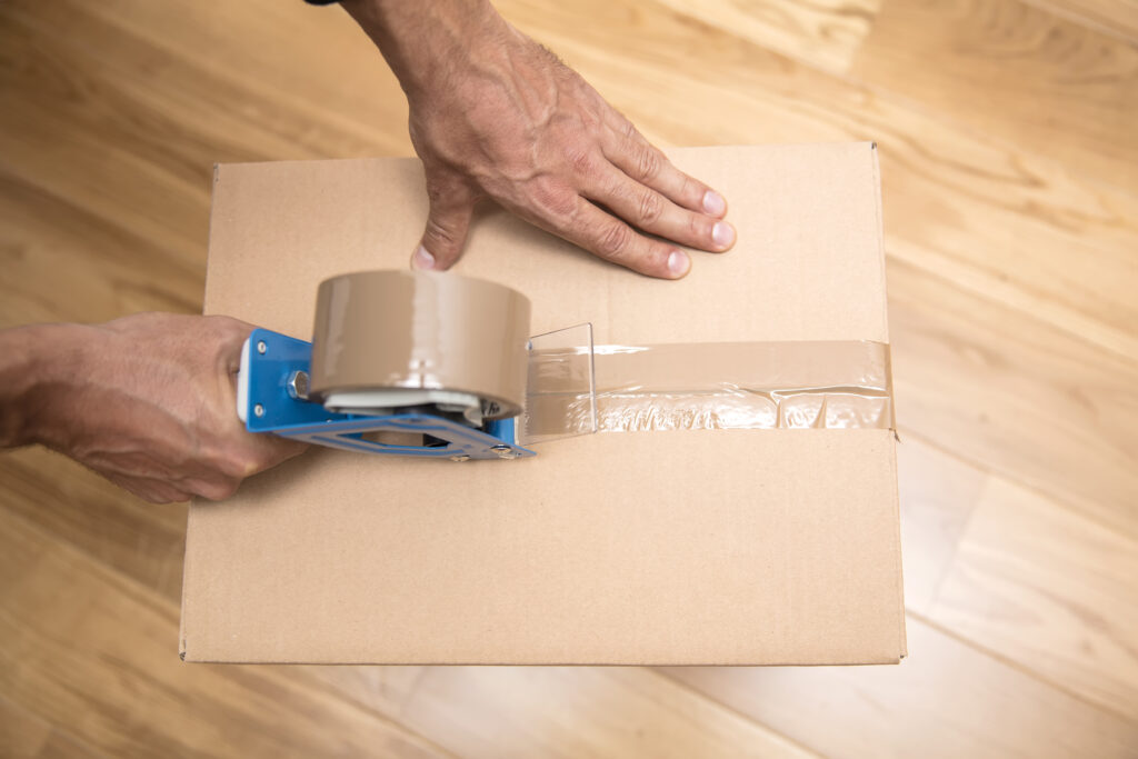 Using tape to close a moving box.